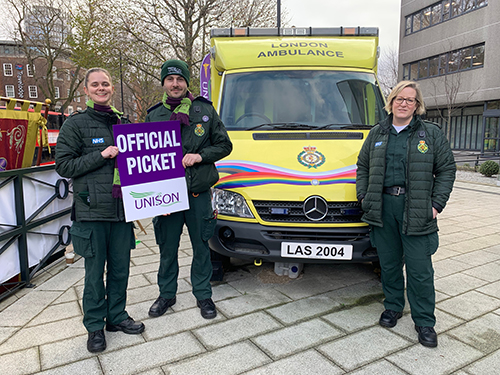 Three members in front of a London ambulance, with an official UNISON strike placard