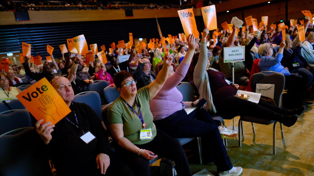 Delegates at health cvonference holding up orange voting papers at health conference, Bournemouth
